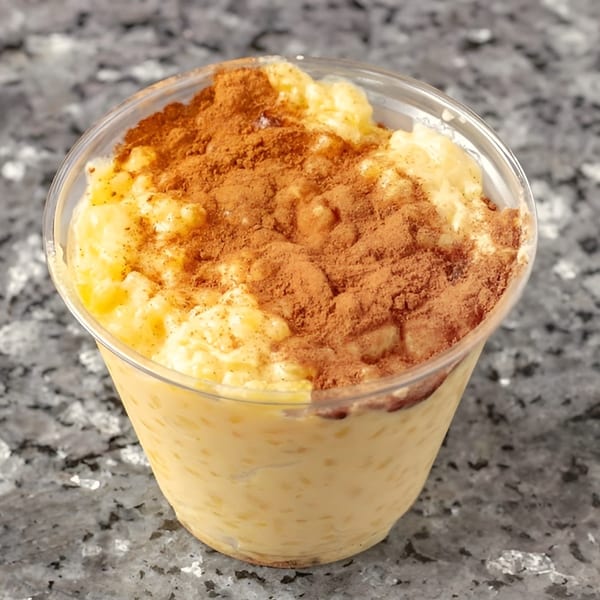 Creamy rice pudding in a clear cup, generously topped with cinnamon powder.